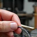 Details einer Hand, die eine Angelrute während eines Reparatur-Workshops repariert.